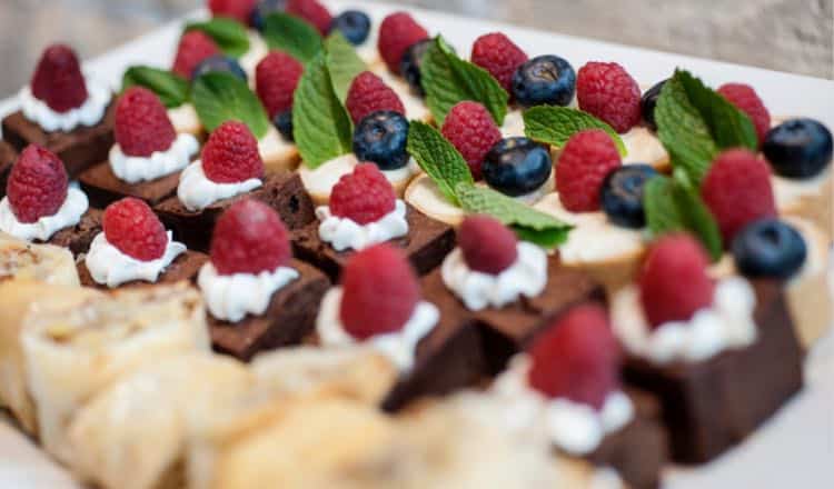 wedding dessert table catering with raspberry brownies, fresh berries and assorted mini desserts