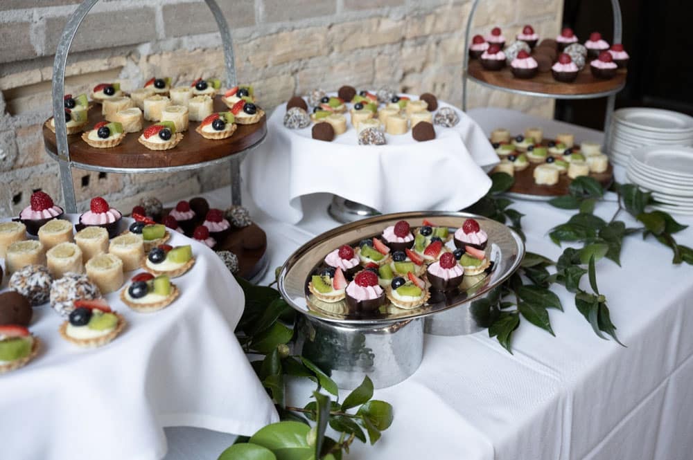wedding dessert table catering with mini fruit tarts, cupcakes and assorted bite-sized desserts